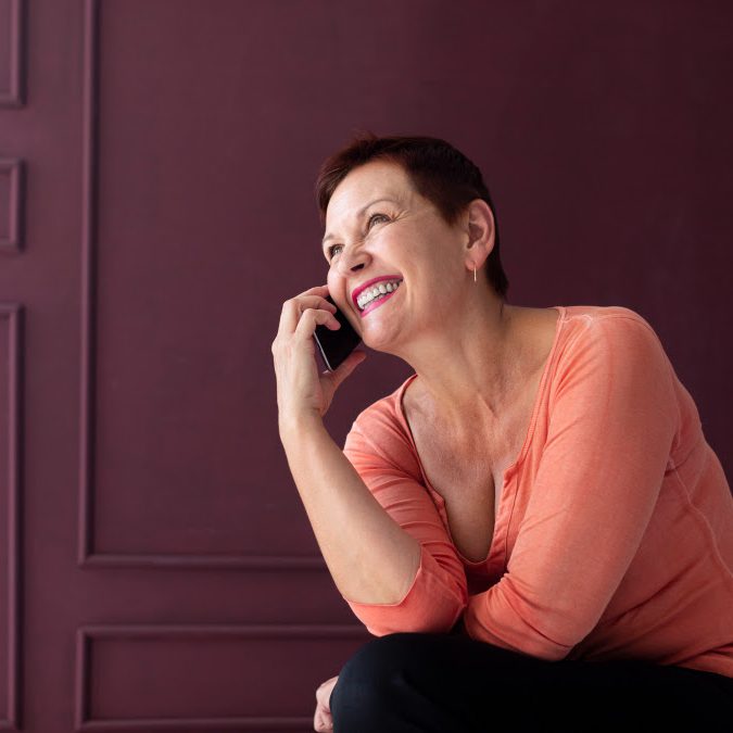 Mujer con chaqueta azul, sonriente, ante un micrófono en un podio.